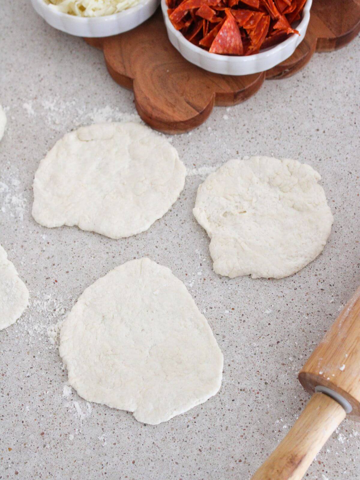 the dough rolled out into 3 circles with a rolling pin and the ingredients around the edge