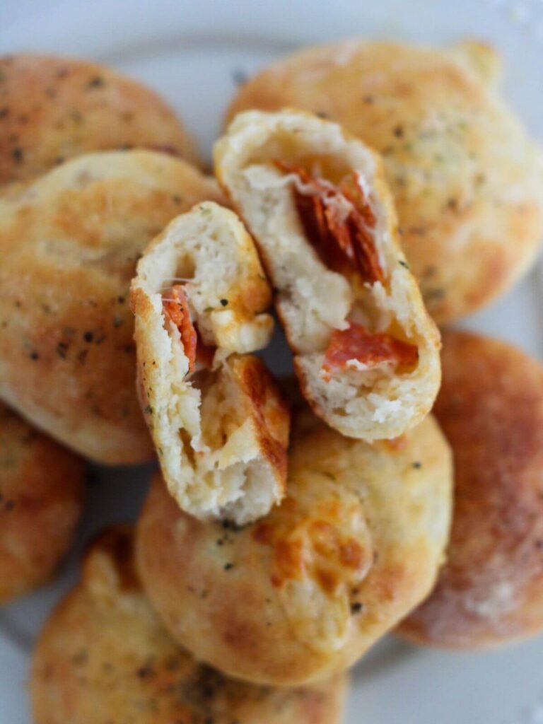 Pizza bites stacked and one cut in half and opened on a white plate