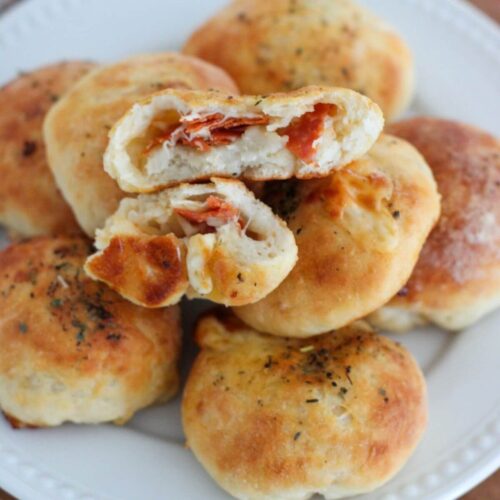 High-Protein Pizza Bites stacked on a white plate with one sliced in half showing the inside