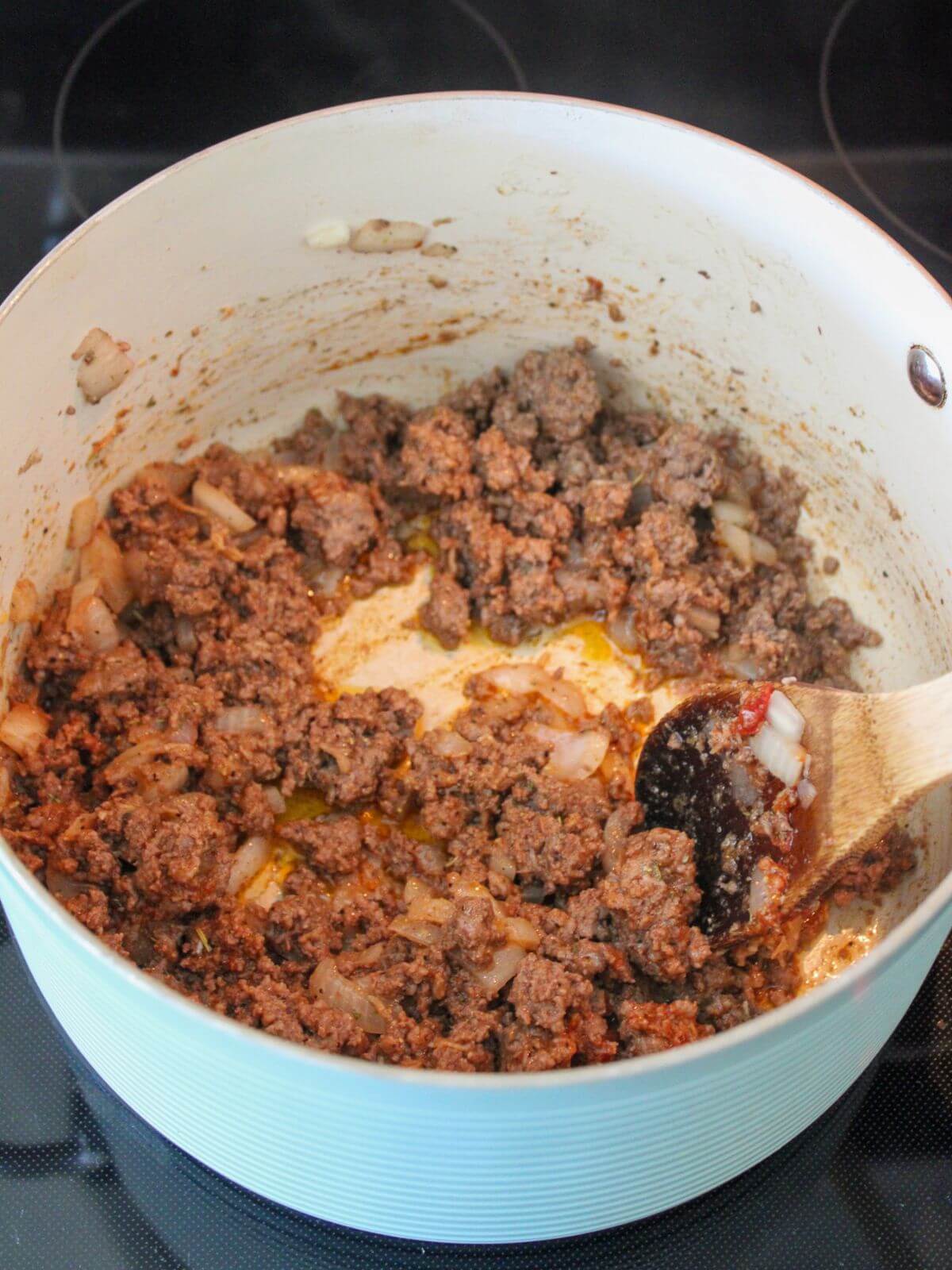tomato paste and garlic added to the ground beef mixture in the stock pan
