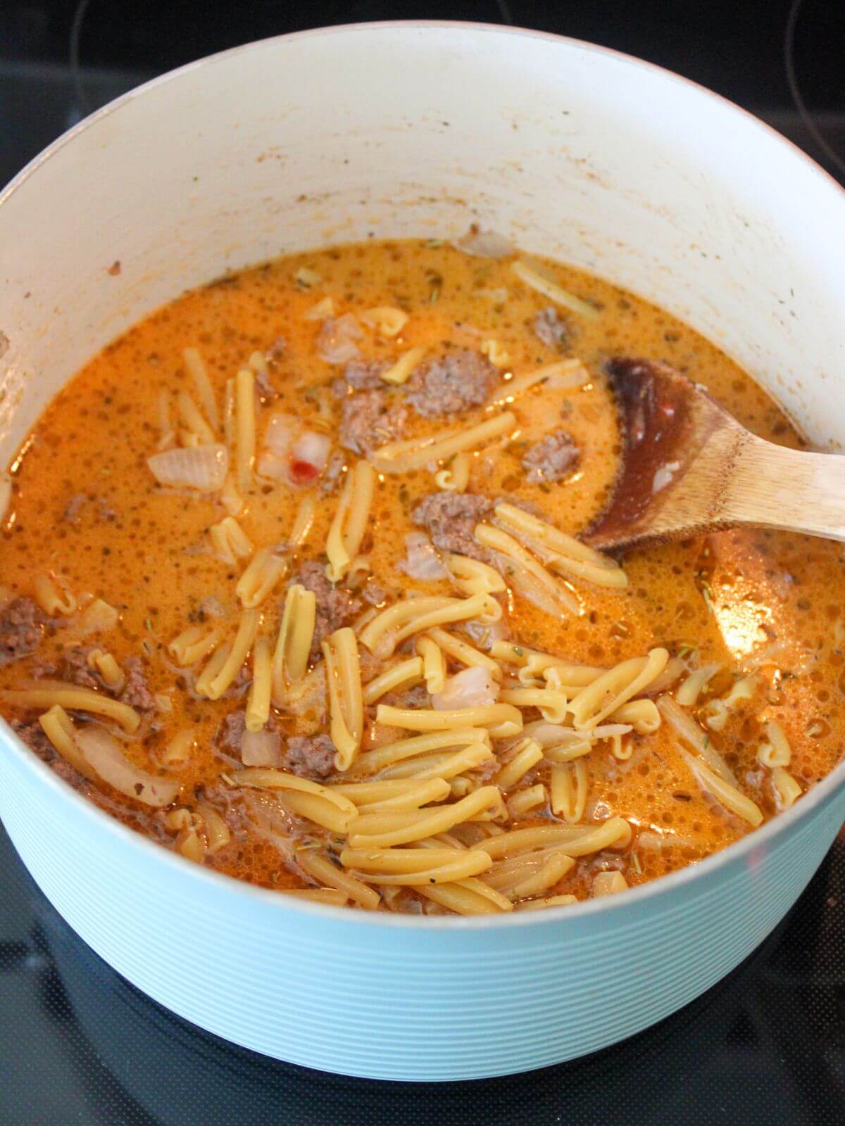 all the pasta and liquids added to the mixture in the stock pan with a wooden spoon