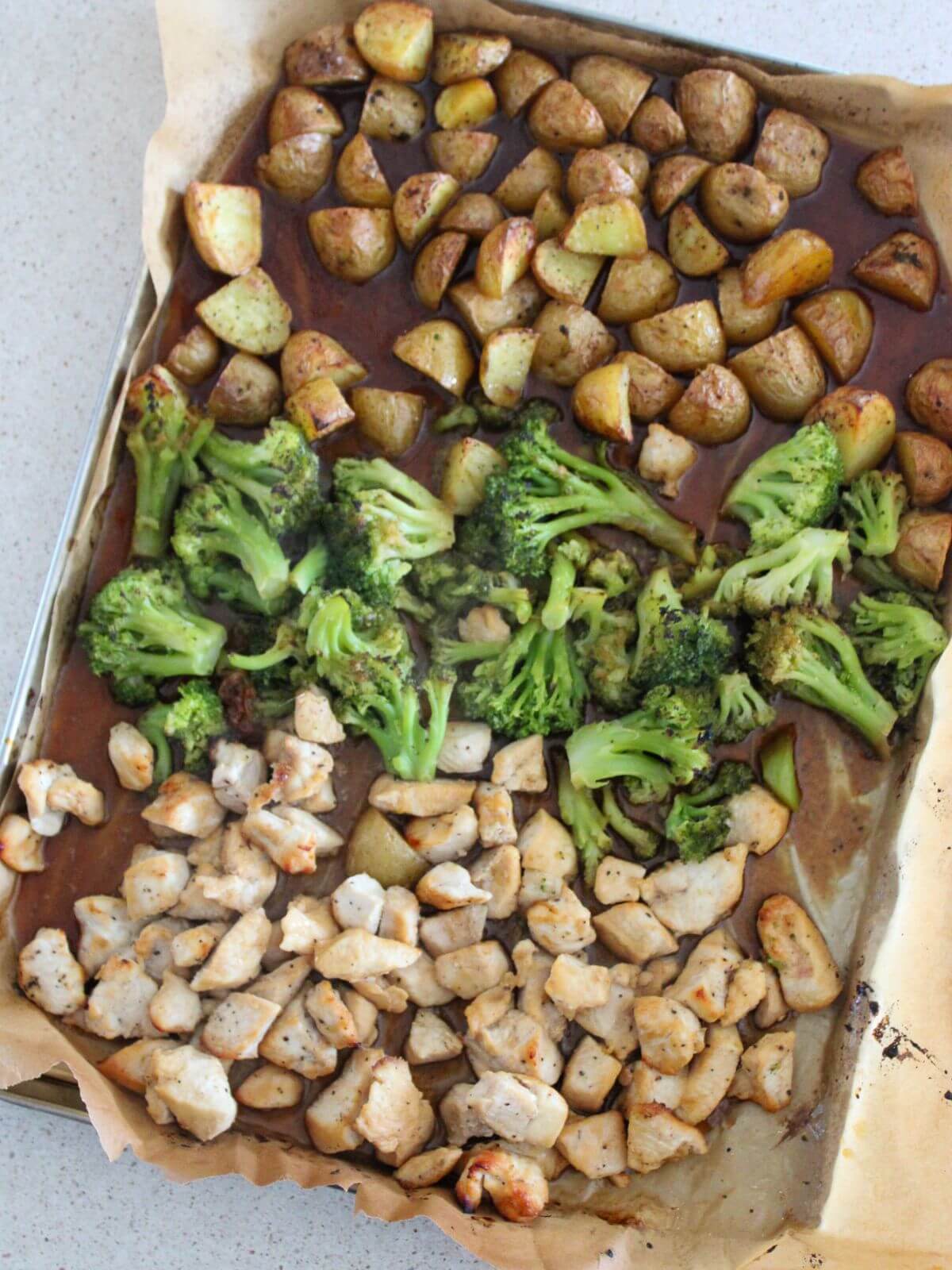 the chicken, broccoli and potatoes all roasted on a sheet pan with parchment paper