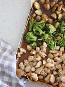 up close of the sheet pan honey garlic chicken on a sheet pan with parchment paper and a plaid napkin next to it