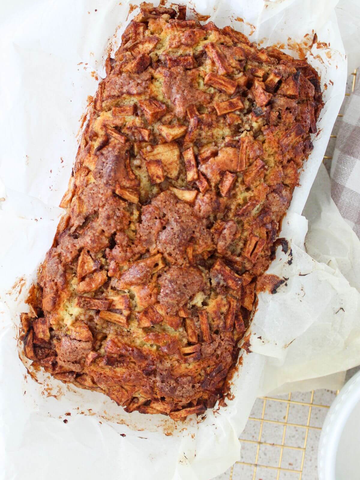 the apple fritter bread baked in a loaf pan with parchment paper
