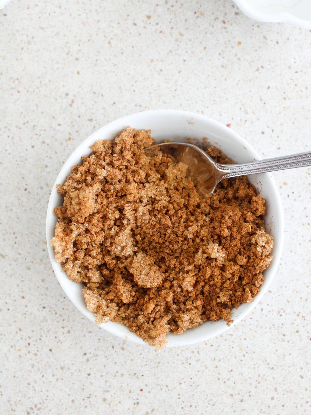 Mixing the cinnamon swirl ingredients together in a white bowl with a silver spoon