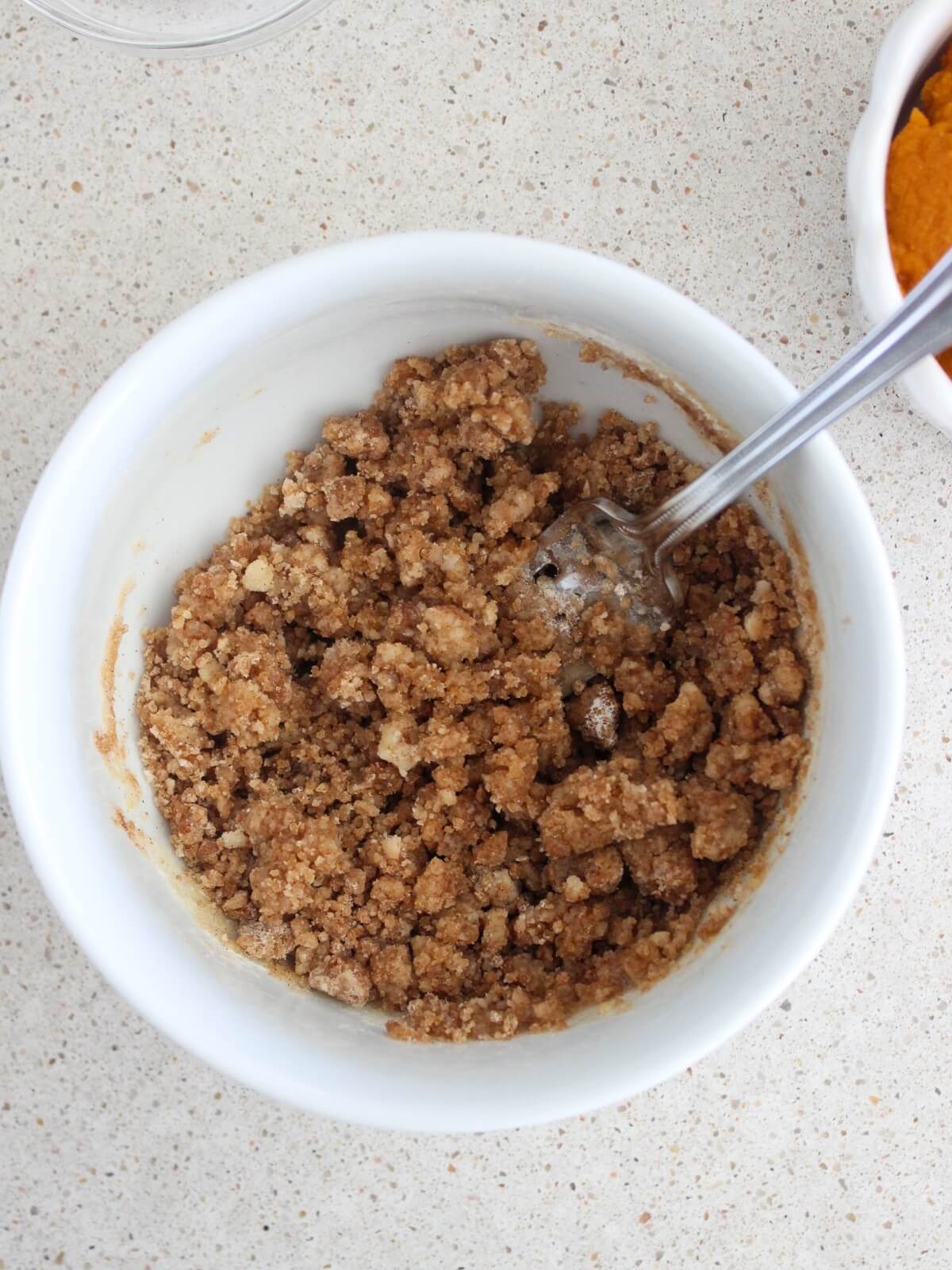 mixing the crumb topping in a white bowl with a silver spoon
