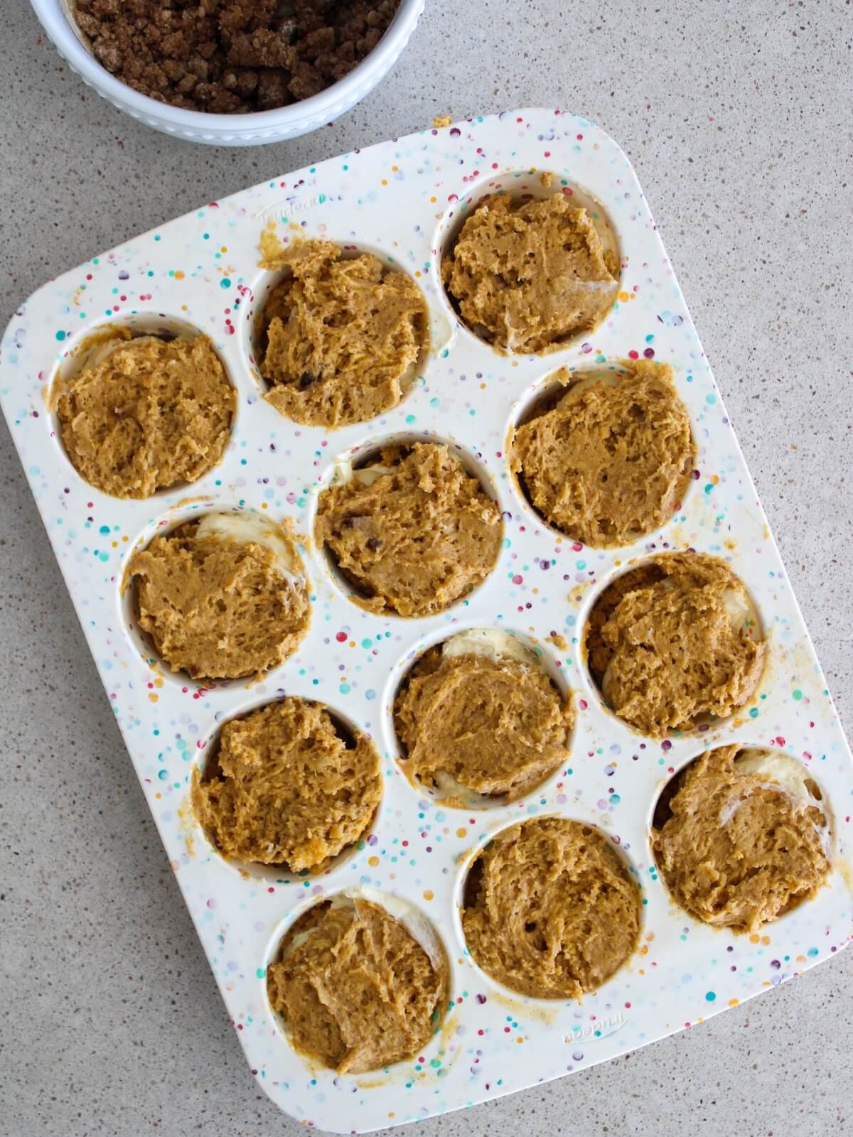 topping the cream cheese mixture with more pumpkin batter in the pan